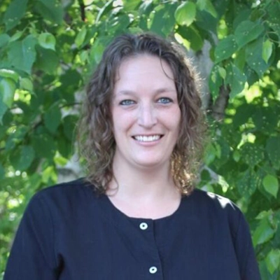 Amy outside smiling in from of greenery.