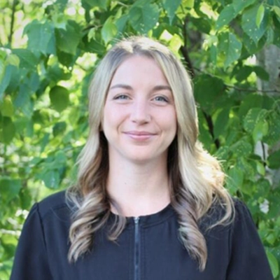 Brooklyn outside smiling in from of greenery.