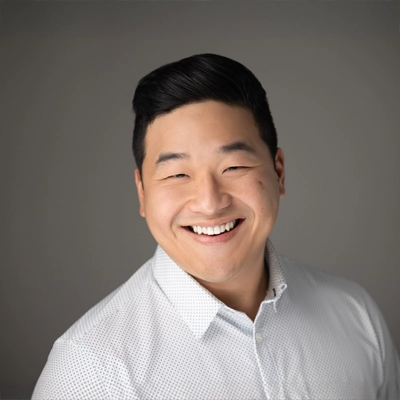 Dennis Shim smiling in a white button up.