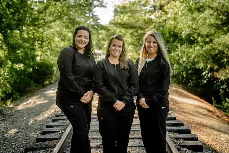 Three team members standing outside smiling.