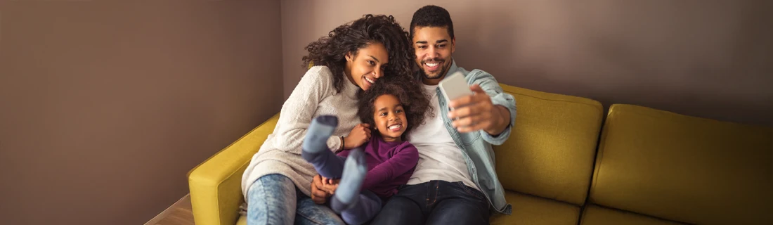 A smiling family of three on the couch.