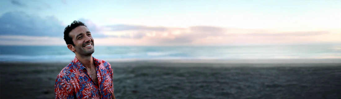 A man smiling while walking on the beach.