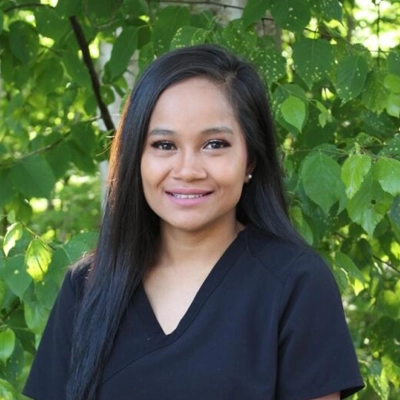 Joell outside smiling in from of greenery.