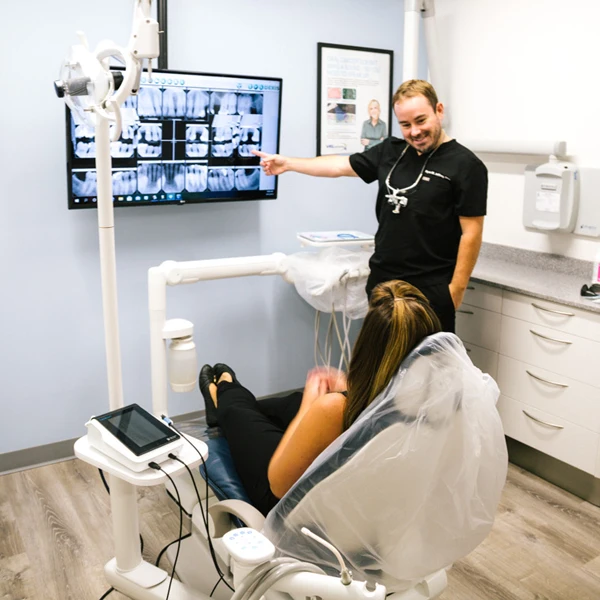 A patient sitting in a chair, looking at their x-rays.