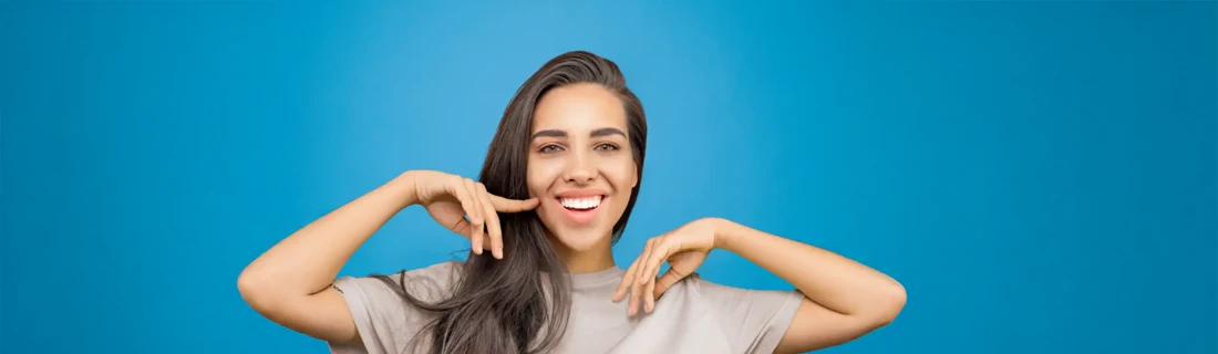 A woman smiling in front of a blue wall.